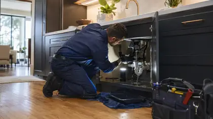 Plumber checking a leak under a kitchen sink